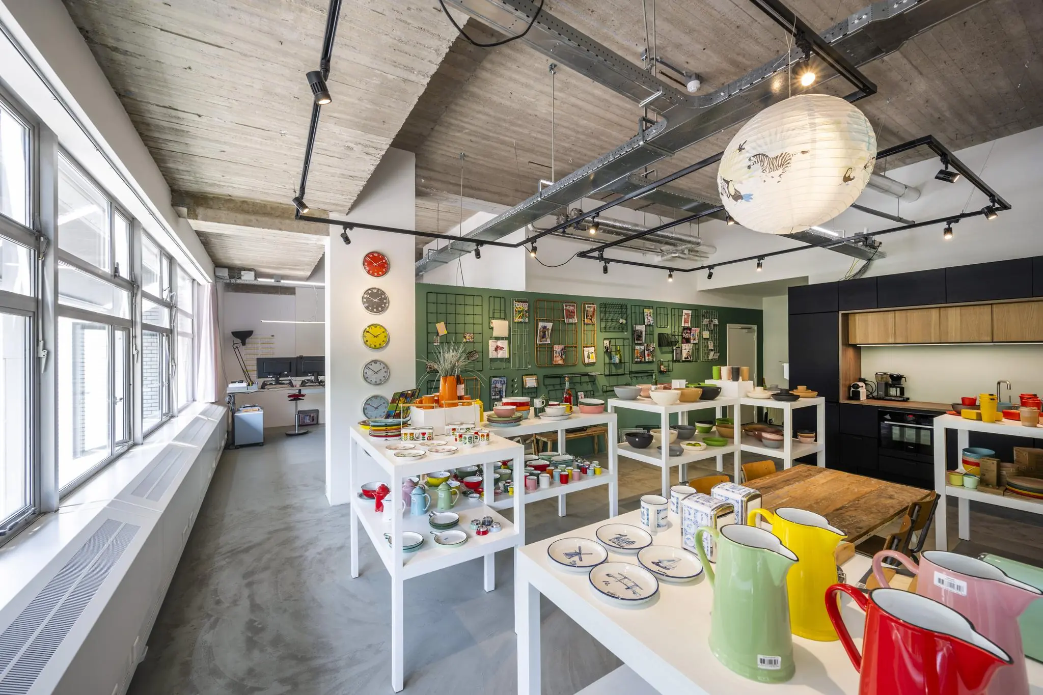 Een moderne showroom aan de Van Leijenberghlaan met kleurrijk servies, designitems en een open kantoorruimte op de achtergrond.